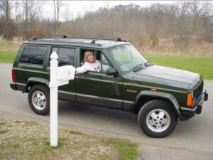 Rural letter carrier Amy Williams delivering mail from her RHD Jeep Cherokee