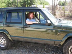 Rural letter carrier Kimberly Earl driving her RHD Jeep Cherokee postal delivery vehicle
