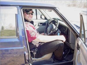 Rural letter carrier Mike Williams in the driving seat of his RHD Jeep Cherokee postal delivery vehicle