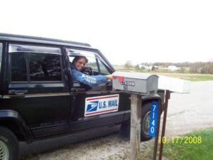 Rural letter carrier Renee Strohm delivering mail from her RHD Jeep Cherokee