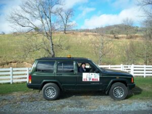Rural letter carrier Tammy Roberts in her RHD Jeep Cherokee postal delivery vehicle