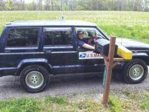 Rural letter carrier Tracy Furlow delivering mail with a RHD Jeep Cherokee
