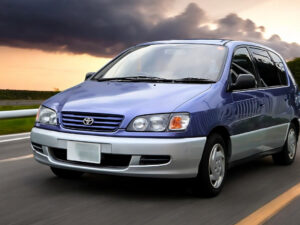 RHD Toyota Ipsum in blue from left front as it drives down a road