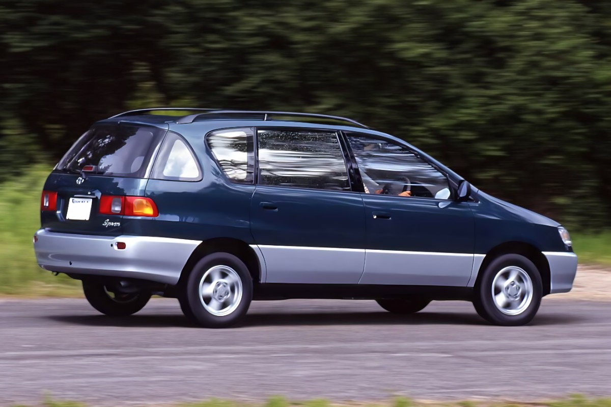 RHD Toyota Ipsum in dark bluw from right side driving down a country road