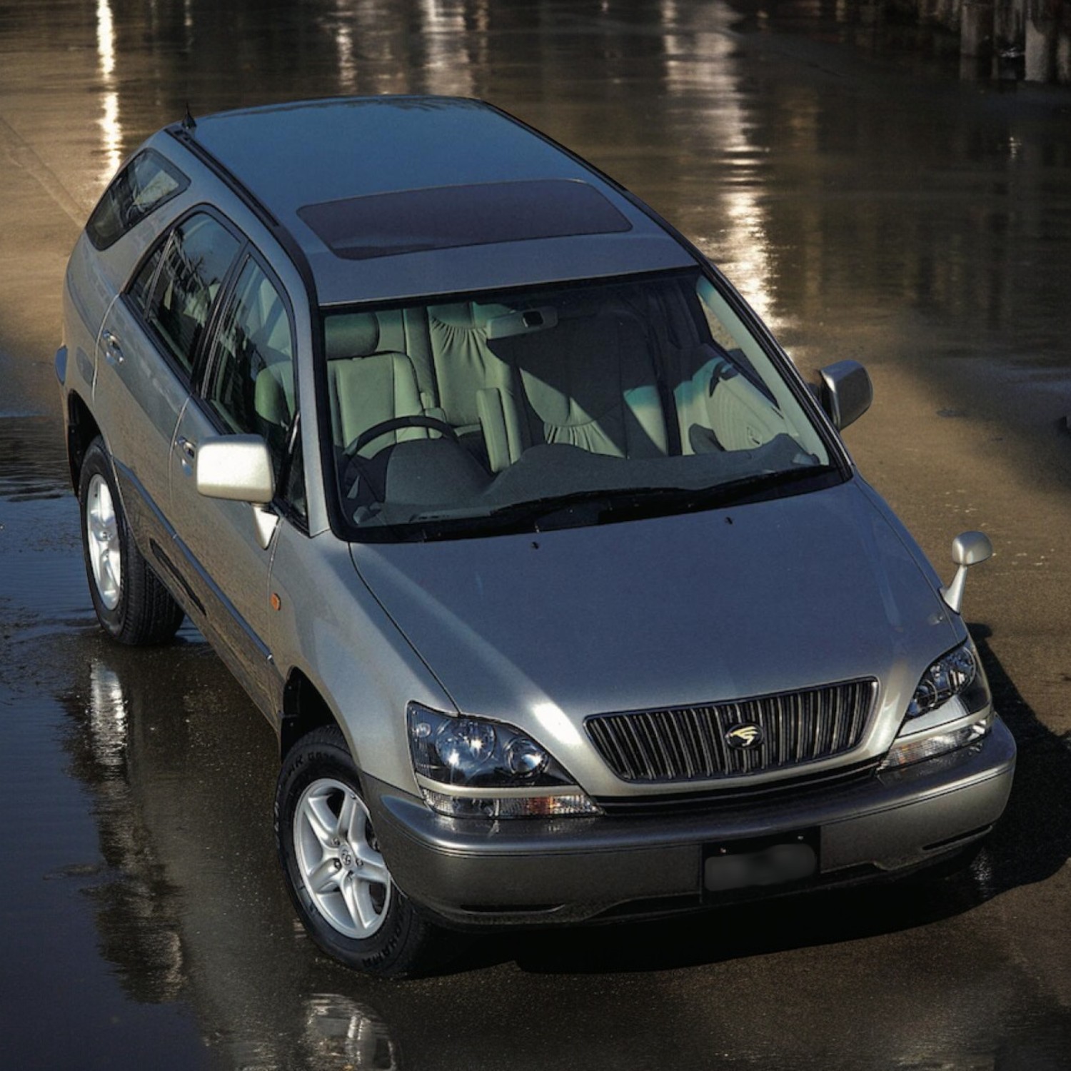 RHD Toyota Harrier (Lexus RX) SUV in champagne silver drone view from right front.