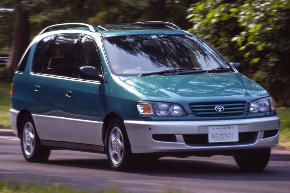RHD Toyota Ipsum in teal from right front as it drives down a road